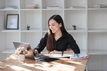 Smiling businesswoman working on her laptop at a home office desk