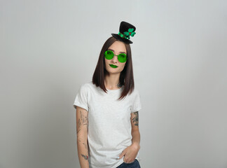St. Patrick's day party. Pretty woman in leprechaun hat and green sunglasses on light grey...