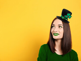 St. Patrick's day party. Pretty woman with green lips in leprechaun hat on golden background. Space for text