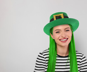 St. Patrick's day party. Pretty woman with green hair and leprechaun hat on light grey background....