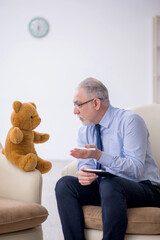 Old male psychologist and soft bear in the room