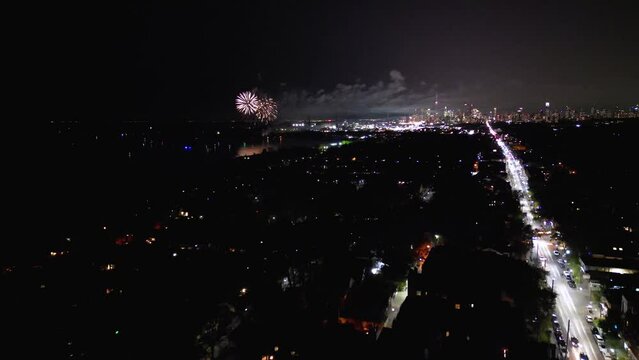 Fireworks exploding over downtown city waterfront lake from aerial drone view during public holiday celebration