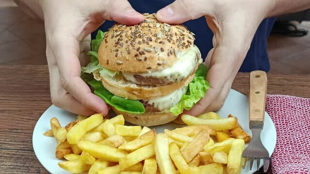 gros plan sur une personne prenant un double burger dans ses mains