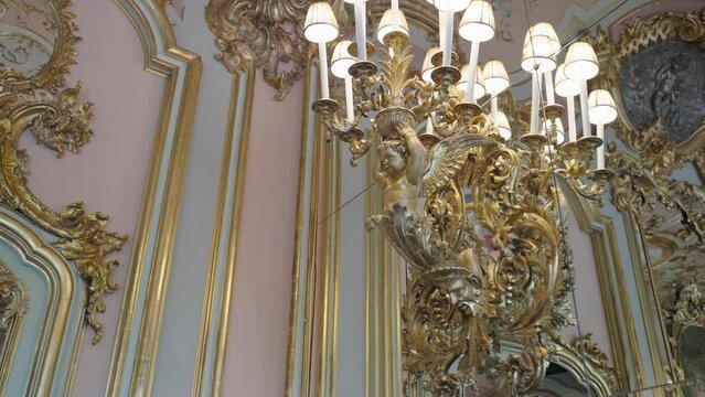 Historical interiour details of an golden angel hoding small lamps and ornamentet wall of Villa Cora in florence tuscany italy