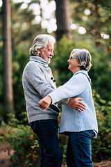 Senior couple in relationship and love hug together in outdoor leisure activity in the forest nature - old people forever together life with happiness
