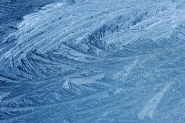 Frost flowers on a frozen flat surface in winter blue ice pattern background texture