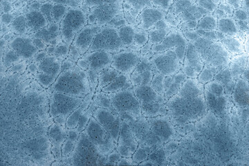 Frost flowers on a frozen flat surface in winter blue ice pattern background texture