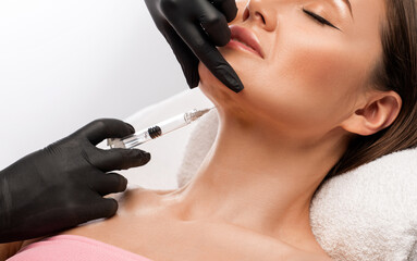 Cosmetologist makes lipolytic injections to burn fat on the chin, cheeks and neck of a woman...