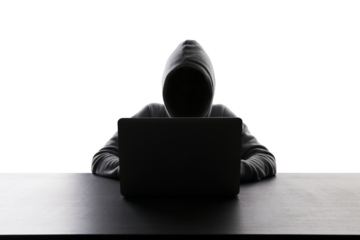 Silhouetted figure in hoodie working on laptop, concept of privacy or hacking