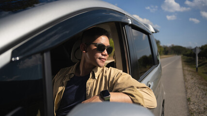 Attractive man in sunglasses driving car and enjoying nature views during summer roadtrip