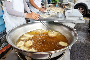 Hawker deep frying the Ham Chim Peng in wok with hot oil, a popular Chinese street food in Malaysia