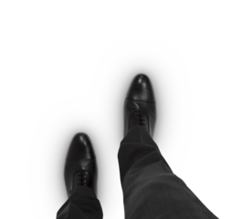 Man's viewpoint looking down at black dress shoes and grey suit pants