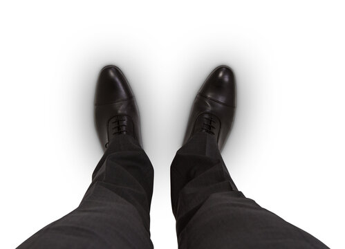 Business professional in black shoes and suit trousers against a white backdrop