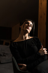 Fototapeta na wymiar Elegant woman in a black dress posing in an apartment. Fashion shooting concept. Valentine's Day