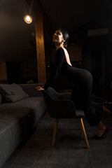 Elegant woman in a black dress posing in an apartment. Fashion shooting concept. Valentine's Day