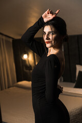 Elegant woman in a black dress posing in an apartment. Fashion shooting concept