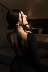 Elegant woman in a black dress posing in an apartment. Fashion shooting concept