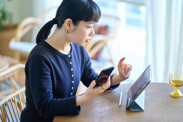 Young woman comparing tablet PC and smartphone