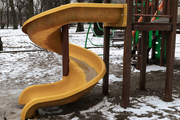 A spiral yellow slide on an abandoned playground