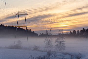 Power towers and electric wires at hazy winter scenery in Finland