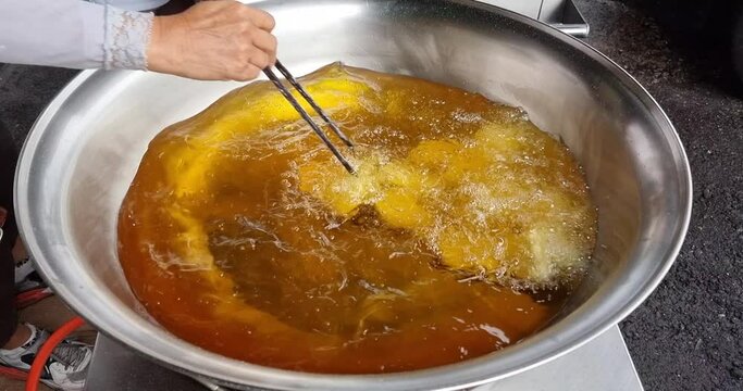 Hawker deep frying the Ham Chim Peng in wok with hot oil, a popular Chinese street food in Malaysia