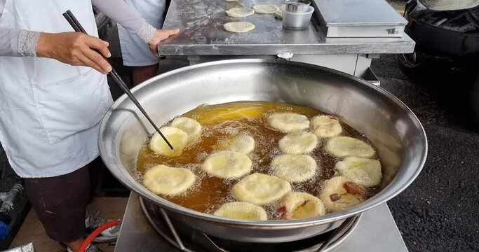 Hawker deep frying the Ham Chim Peng in wok with hot oil, a popular Chinese street food in Malaysia
