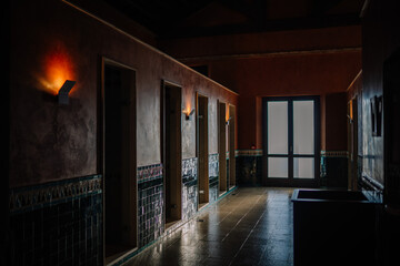 Sotogrante, Spain - January 27, 2024 - Dimly lit hallway with warm wall sconces, tiled accents, and a glowing exit at the end, exuding a quiet ambiance.