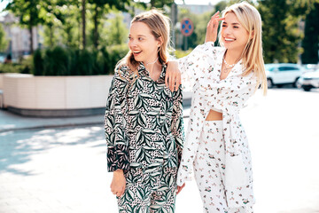 Two young beautiful smiling hipster female in trendy summer costumes  clothes. Sexy carefree women posing in the street. Positive models having fun at sunny day. Going crazy
