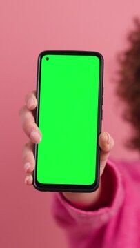 Happy woman showing mobile phone with chromakey in studio. Vertical footage
