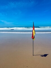 Yellow and red flag on the sand beach, empty beach, blue seascape