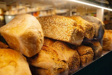 Assorted Freshly Baked Bread Loaves Displayed on Clean and Well-Lit Bakery Shelf