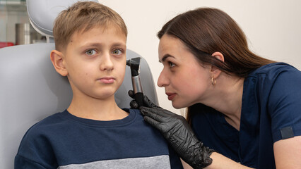 little boy, fair-haired teenager, sitting in an otolaryngologist's office, having an ear...