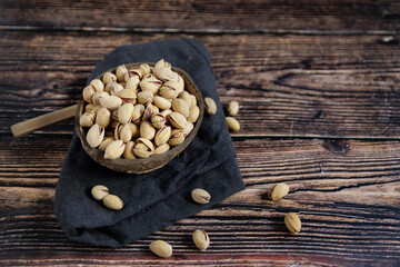 Pistachios in a bowl on a wooden table.