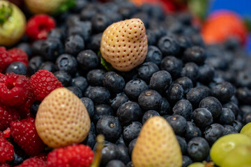 sample of black cranberries next to white strawberries