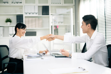 Obraz premium Businessman and Businesswoman sitting at desk, checking hand together in office after success dealing business with smile of happiness.
