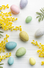 Colorful easter eggs  and mimosa flowers on wooden table.