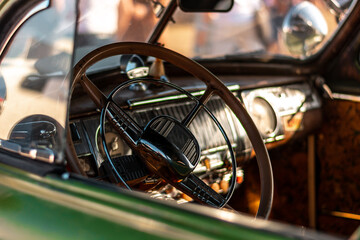Close up of the steering wheel and dashboard of a vintage car.