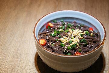 a bowl of Hot and Sour Fern Root Noodles on table. Spicy Chinese Sichuan food