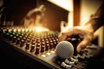 Hand sound engineer holding microphone on audio mixer in live broadcasting studio producer for...