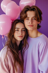 Boy and girl stand next to each other holding balloons.