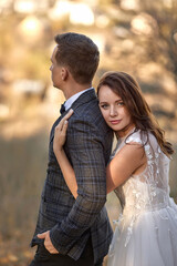 Fototapeta premium beautiful sensual bride in white wedding dress and groom standing outdoor on natural background