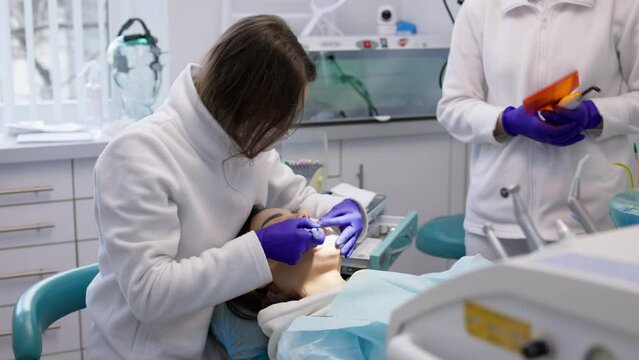 A young woman is undergoing treatment in a modern dental clinic. The concept of dental treatment, whitening, installation of veneers and braces, cleaning the oral cavity.