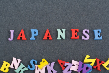 Japanese word on black board background composed from colorful abc alphabet block wooden letters, copy space for ad text. Learning english concept.