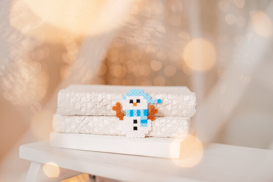 Handmade perler bead snowman decoration placed on cozy towels for Christmas.