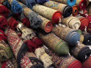 A angled view of a variety of rolled handmade authentic traditional patterned floor rugs. Woolen or...