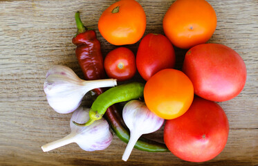 Fresh yellow and red tomatoes, hot peppers and garlic on a cutting board 
