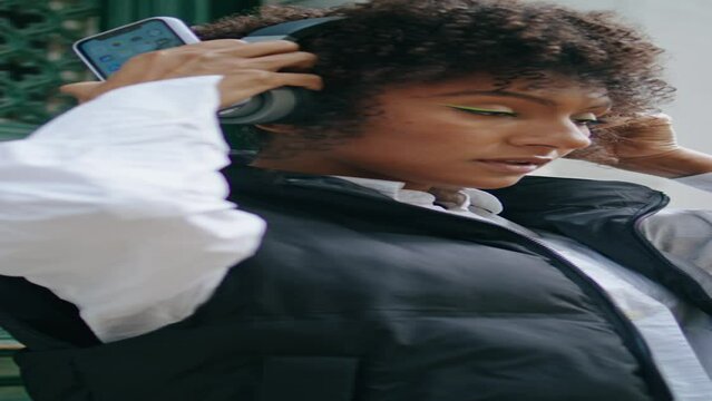 Woman wearing wireless headphones at street close up. Girl in headset vertical