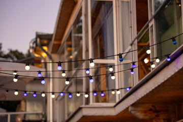 Decoration colorful lights over a street with windows. Colorful Christmas lights for a celebration in a restaurant street in Bulgaria.
