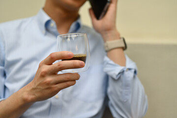 Close-up of an unrecognizable businessman business talking on the smartphone while sipping a coffee, Outdoor