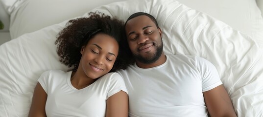 Fototapeta premium African american couple in white clothes happily sleeping on bed with copy space for text placement
